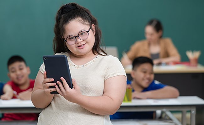 Portrait of young down syndrome girl holding tablet computer in hand with happiness and self-confident.